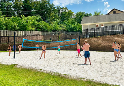 a group of people playing volleyball on a sand court
